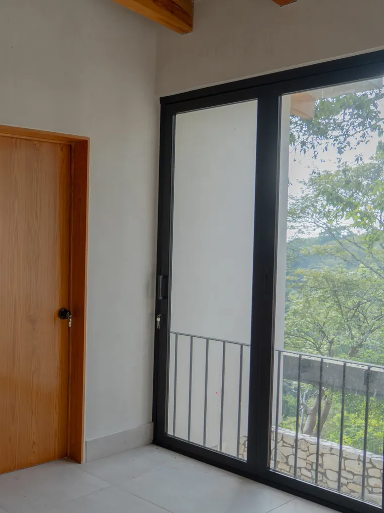 Puerta de madera y ventanal hacia el balcón y el bosque